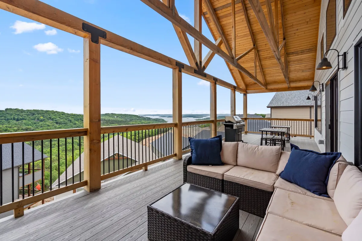A spacious and stylish outdoor seating area under a wooden pergola with an expansive view of the hills. Comfortable seating and an outdoor grill invite relaxation, entertaining, or unwinding after a day outdoors while soaking in the scenery.
