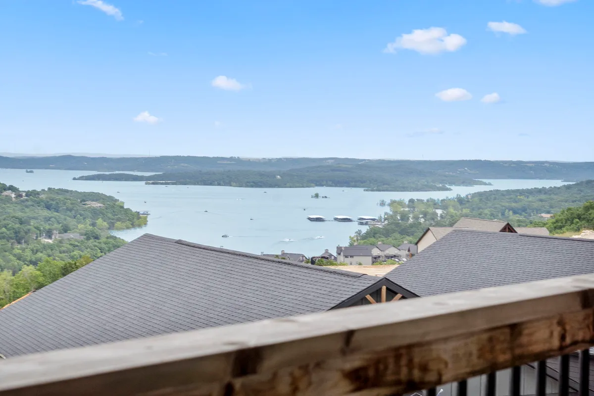 A breathtaking panoramic view of Table Rock Lake, with calm blue waters surrounded by rolling hills. The scene includes visible boating activity on the lake and hints of hiking trails meandering through the lush greenery.