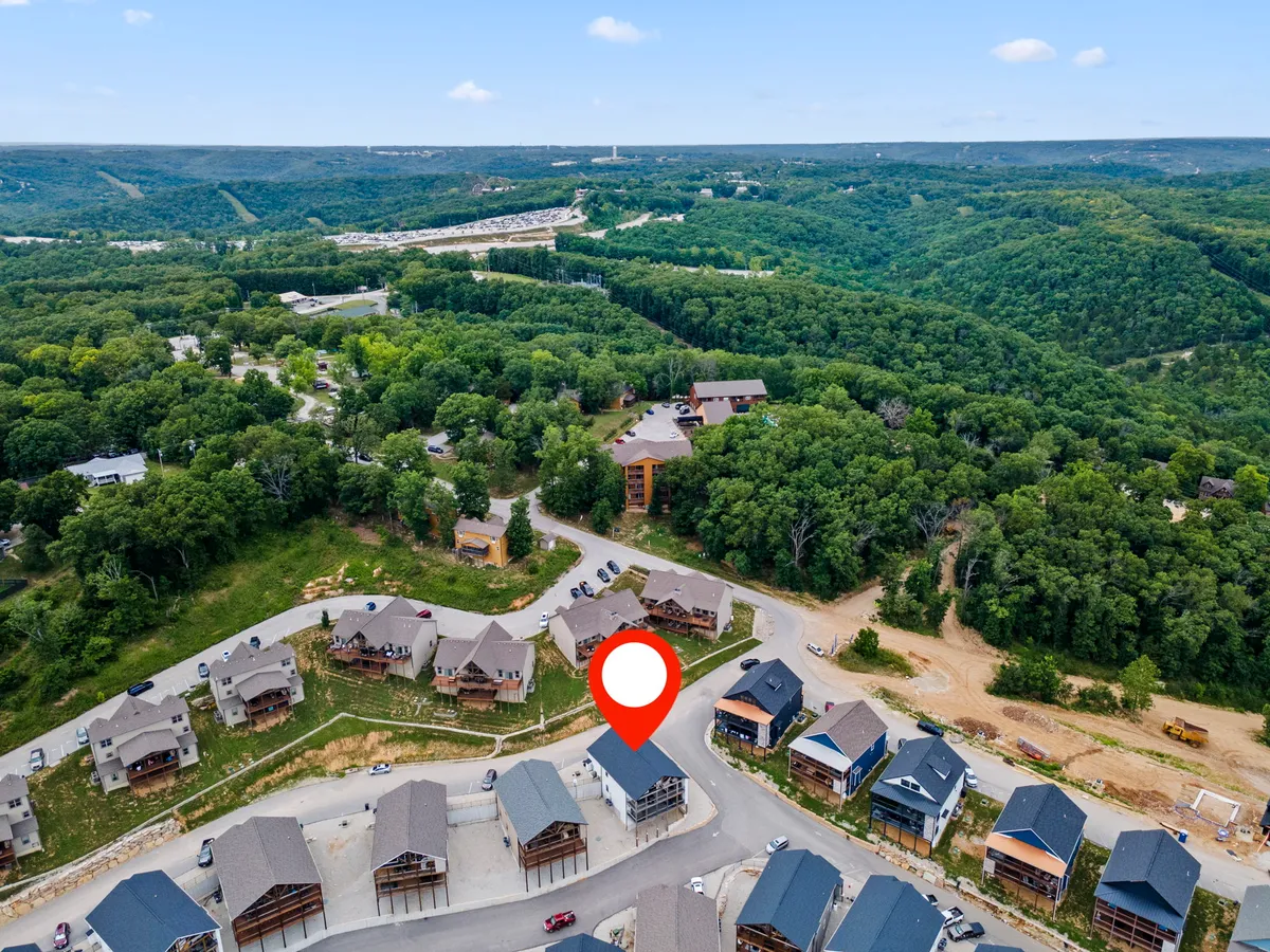 A scenic vista featuring lush green hills, a winding road, a cluster of homes, and open spaces ideal for hiking and nature walks. The tranquil atmosphere highlights natural exploration opportunities close to the property.