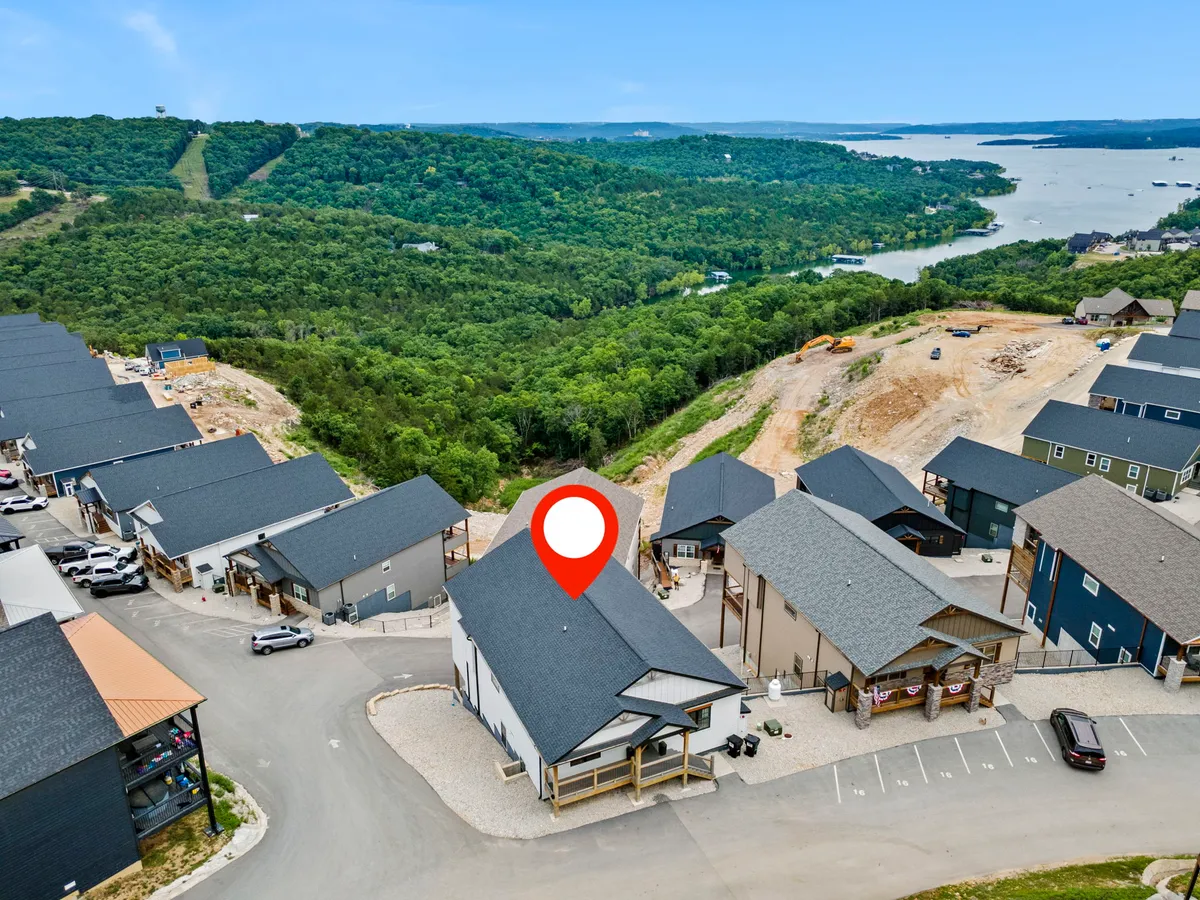 This exterior shot features newly constructed homes set amidst lush green landscapes with a scenic lake view in the background. The community vibe and natural setting evoke the feeling of a shared getaway and opportunities for booking neighboring homes together.