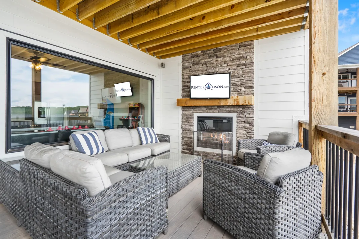 An inviting exterior setting with a comfortable seating area, glowing fireplace, large windows, and an outdoor TV. The space is perfect for relaxing, entertaining, or winding down with friends and family after a day of activity.